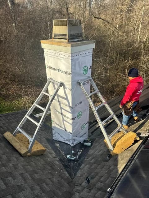 Chimney wrapped in house wrap with worker on roof